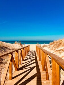 A serene wooden walkway leading to a peaceful beach in Vejer de la Frontera, Spain.