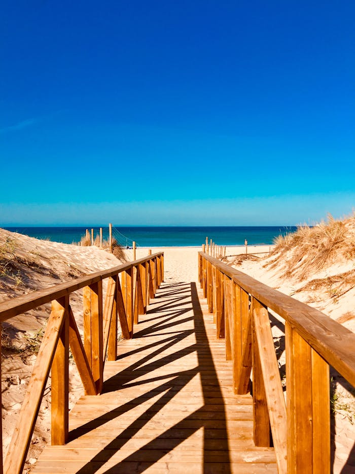 A serene wooden walkway leading to a peaceful beach in Vejer de la Frontera, Spain.