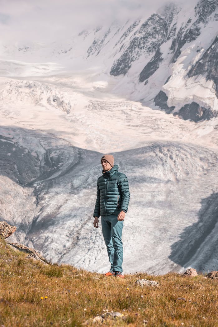 A man in winter clothing hiking in Zermatt, Switzerland, surrounded by majestic snowy mountains.