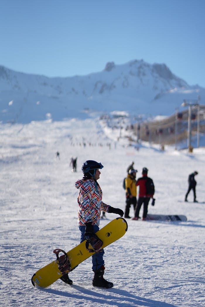 A snowboarder stands ready on a sunny snow-covered mountain slope, perfect winter adventure.