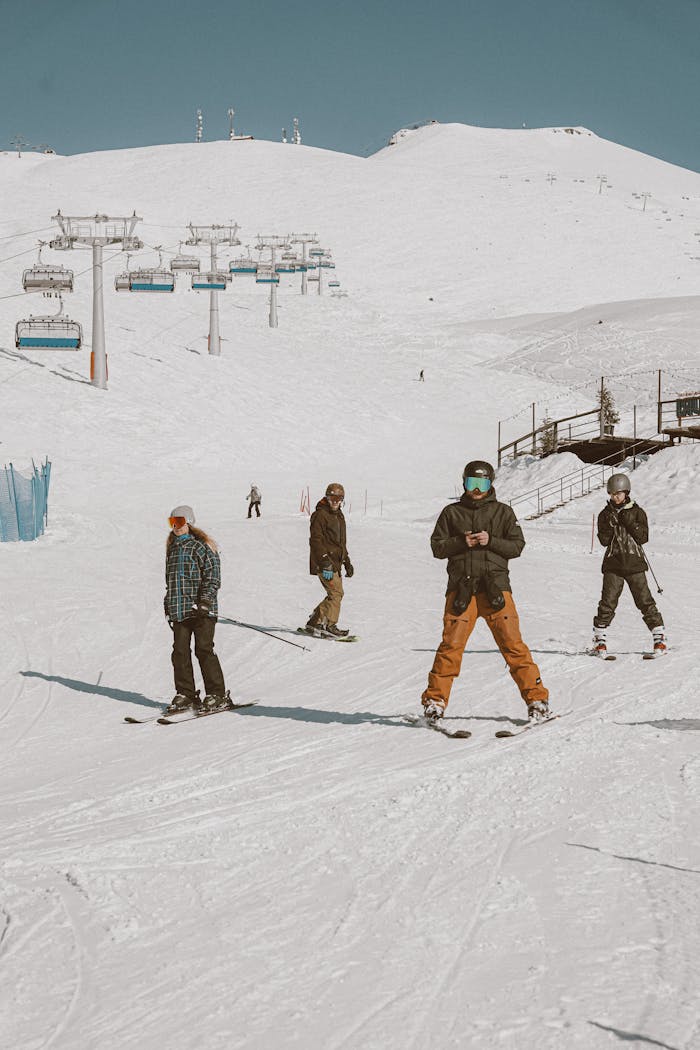 Skiers descending a snowy mountain slope under a clear blue sky, enjoying winter sports.