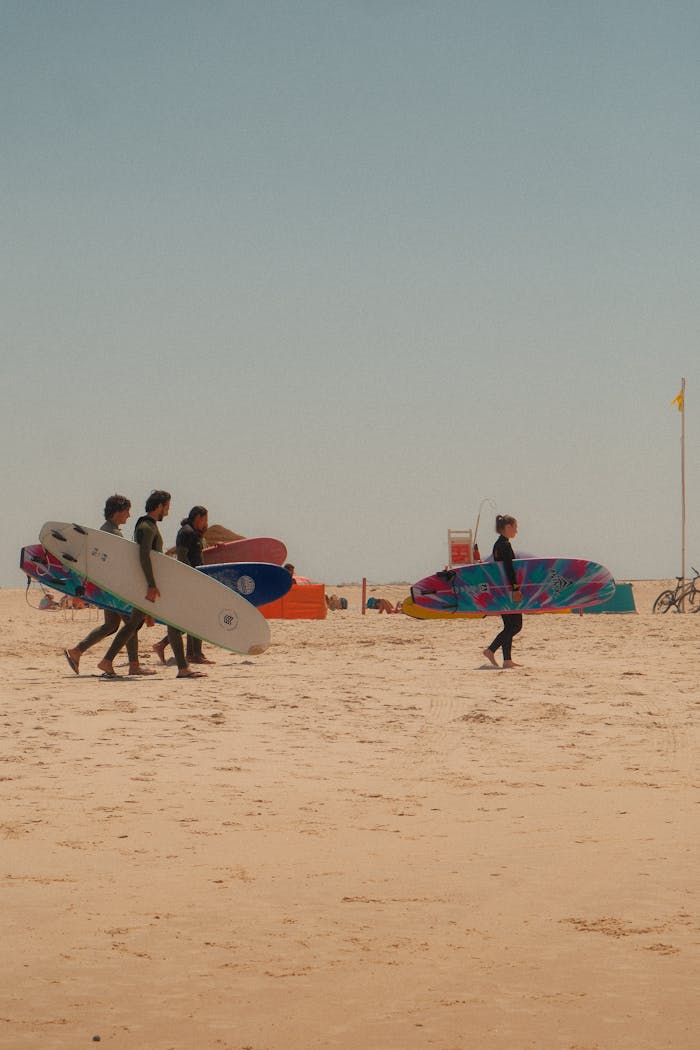 Surfers with boards walking on a sunny beach, ready for adventure.