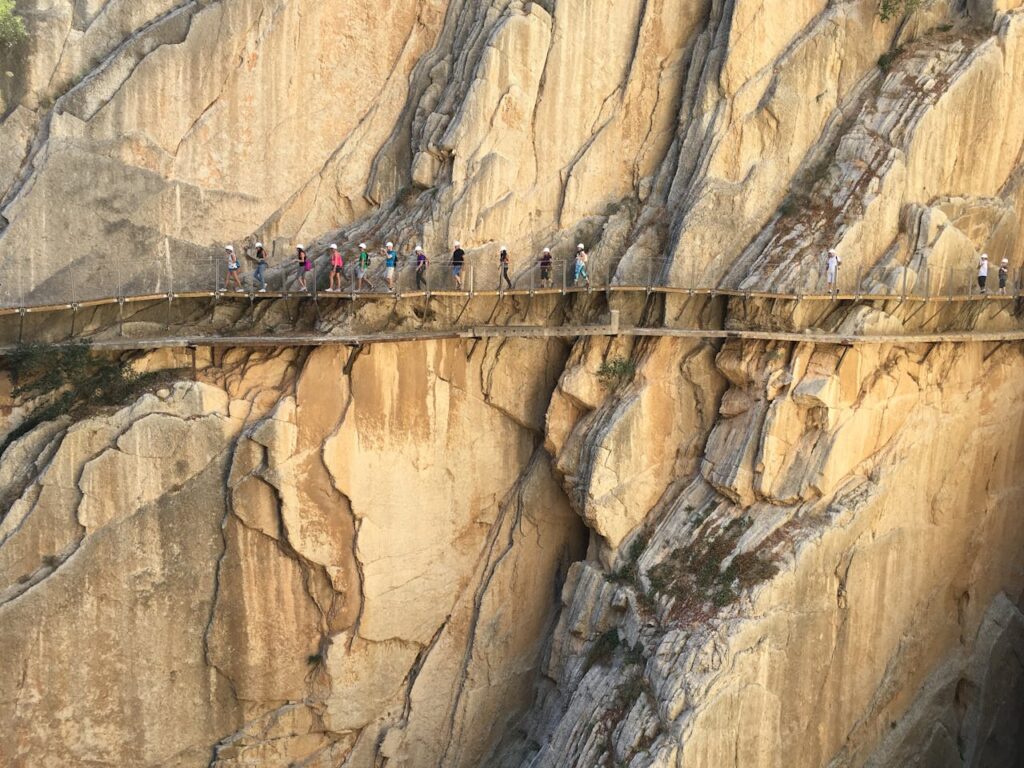 pexels-photo-6663239 Adventurers walking the narrow Caminito del Rey path against stunning cliff backdrop in Spain.