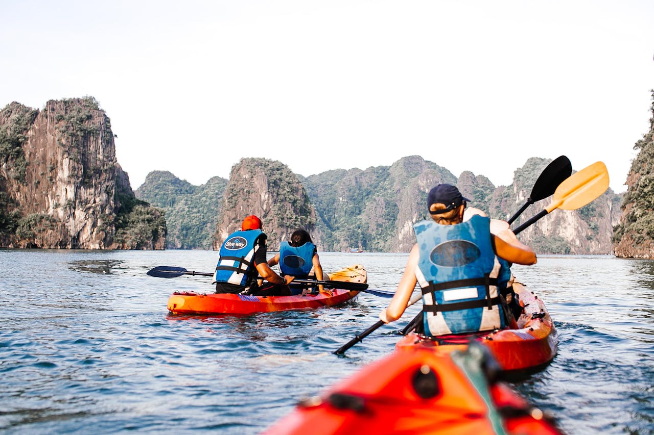 Tourists kayak through scenic limestone cliffs of Halong Bay in Vietnam, capturing a perfect adventure moment.