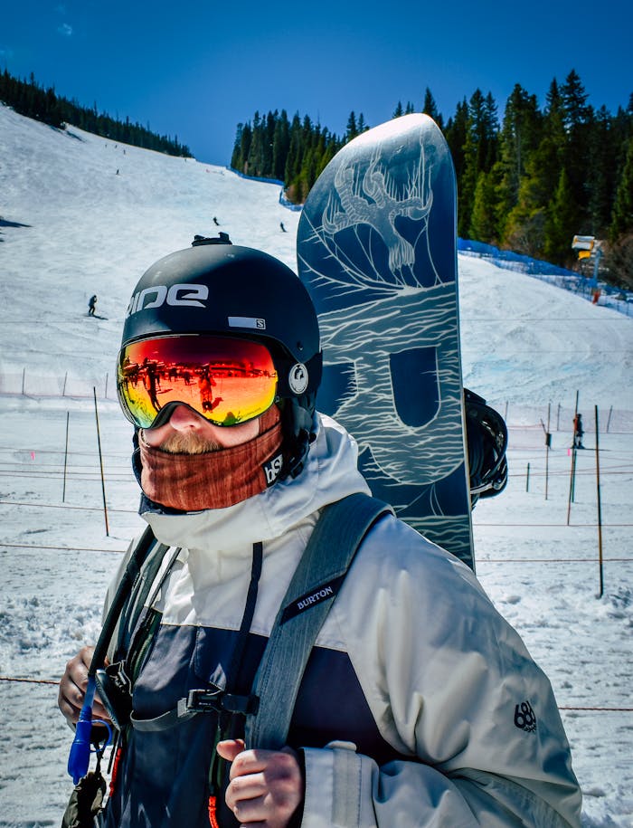 Snowboarder with goggles and helmet on a sunny winter day in the mountains.