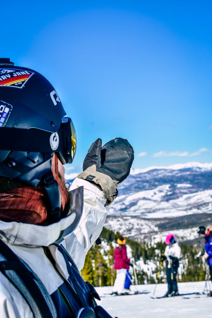 A skier signals to friends on the snowy slopes with breathtaking mountain views, perfect for winter sports enthusiasts.