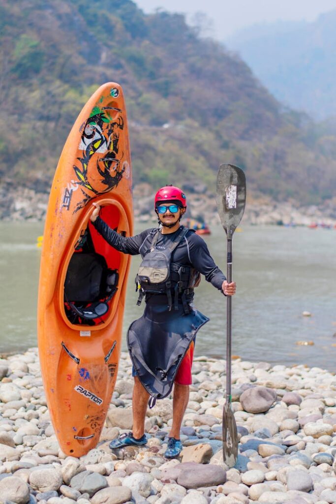 Man standing next to kayak holding a paddle in Rishikesh, ideal for adventure travel themes.
