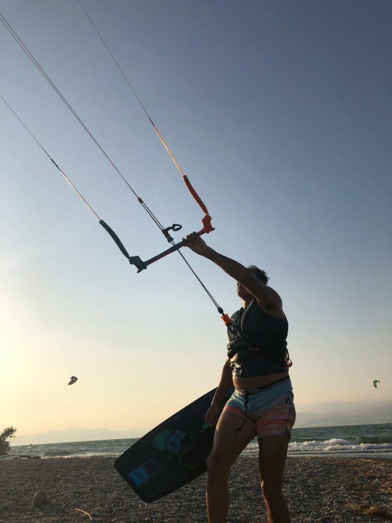 A kitesurfer preparing to launch on a windy beach during sunset, showcasing adventure and water sports.